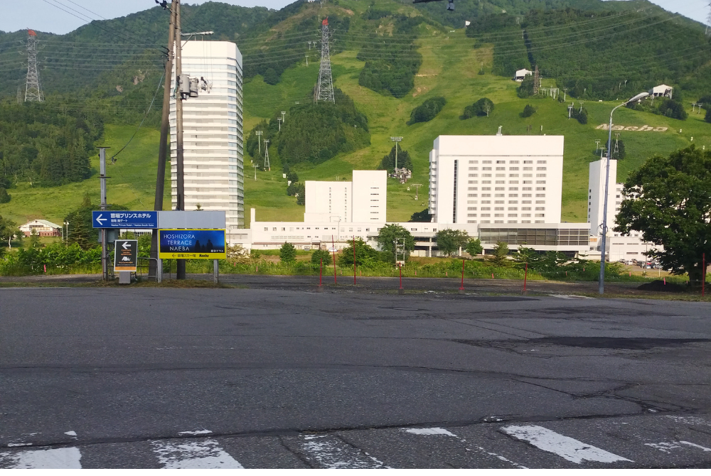 「車で山道を走行中に撮影した、緑に囲まれた山の斜面と道路」