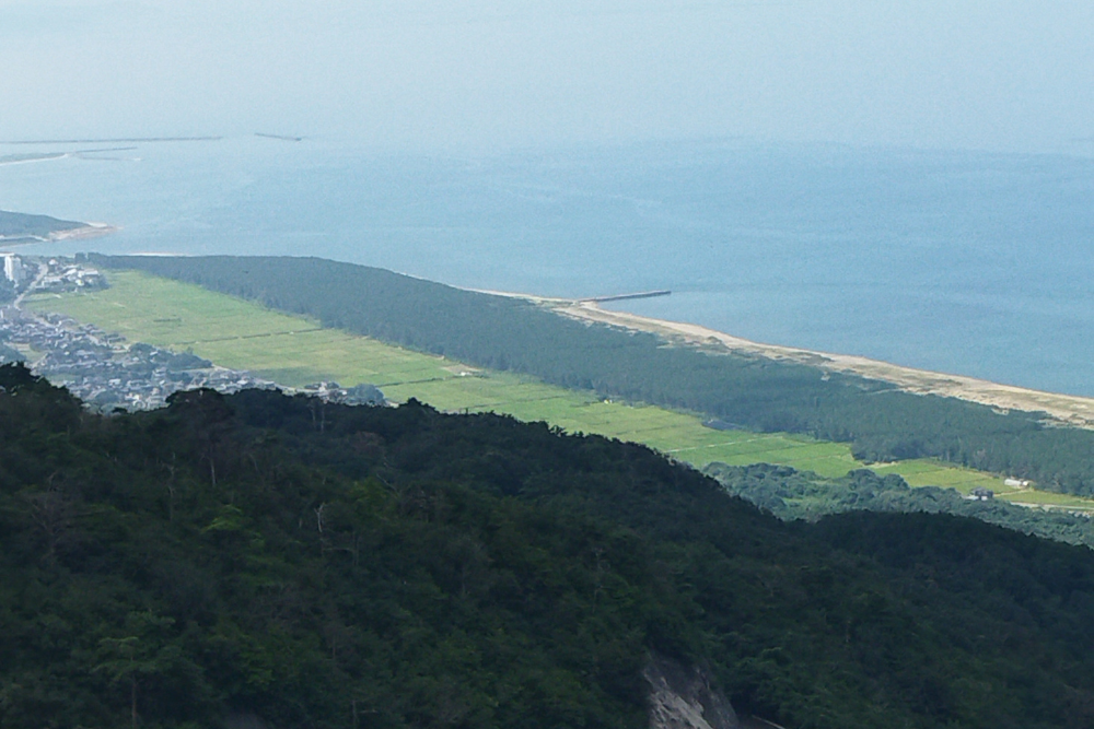 「山の上から望む海岸線と広い田園風景」