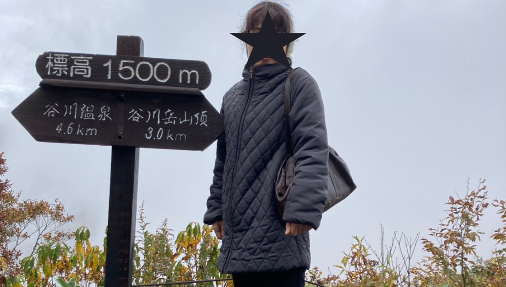 「標高1500mの標識の前で記念撮影する女性」